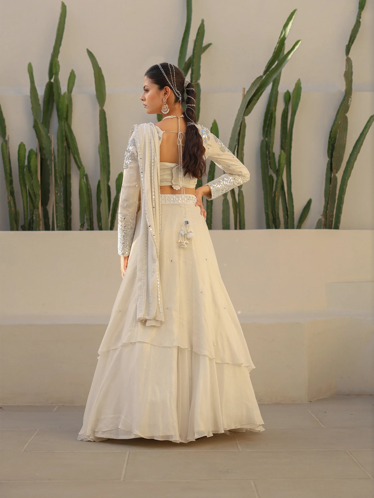 Back view of a woman wearing a white drape saree with mirror work.