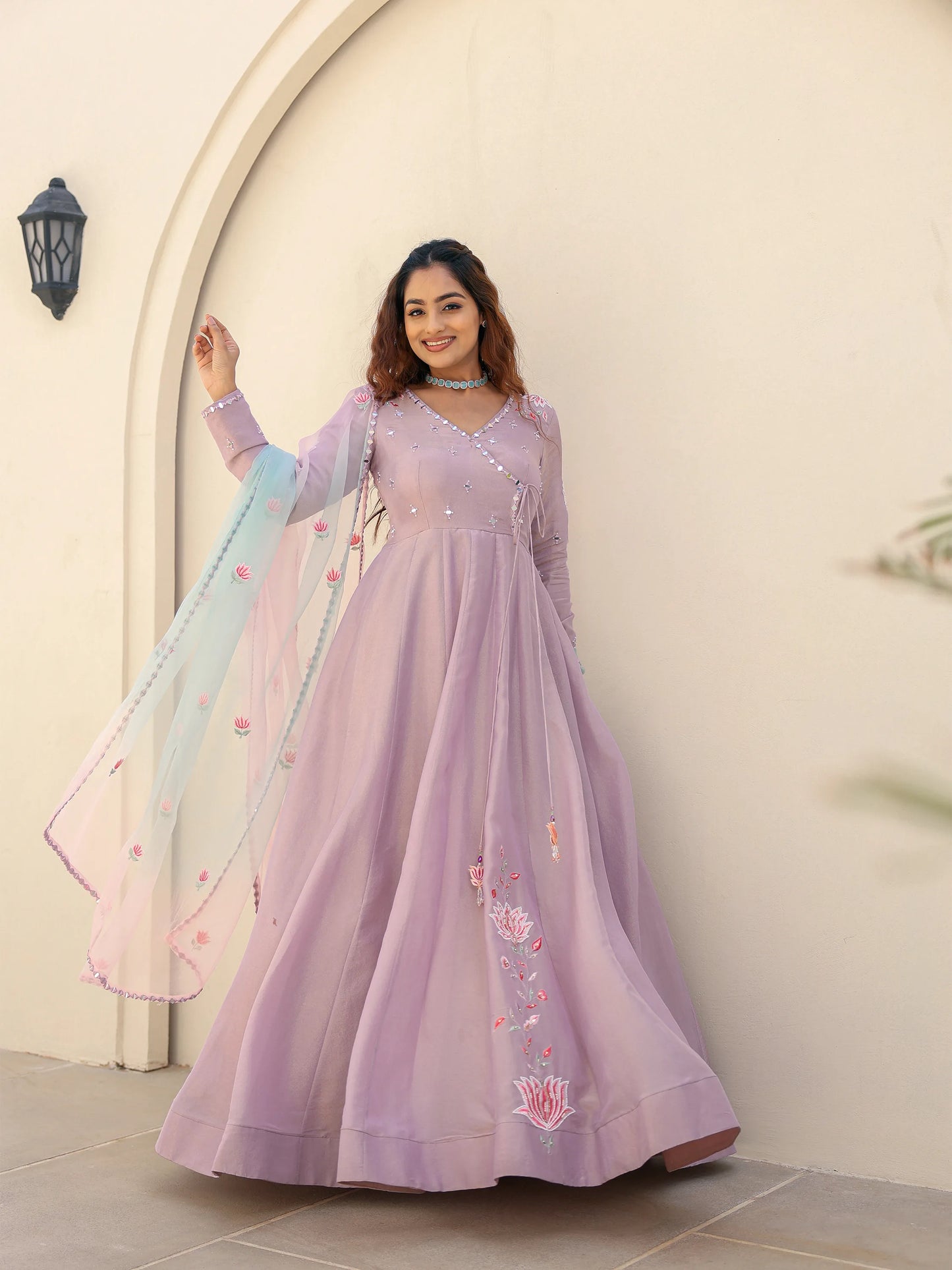 Woman wearing a lilac anarkali suit with floral embroidery.