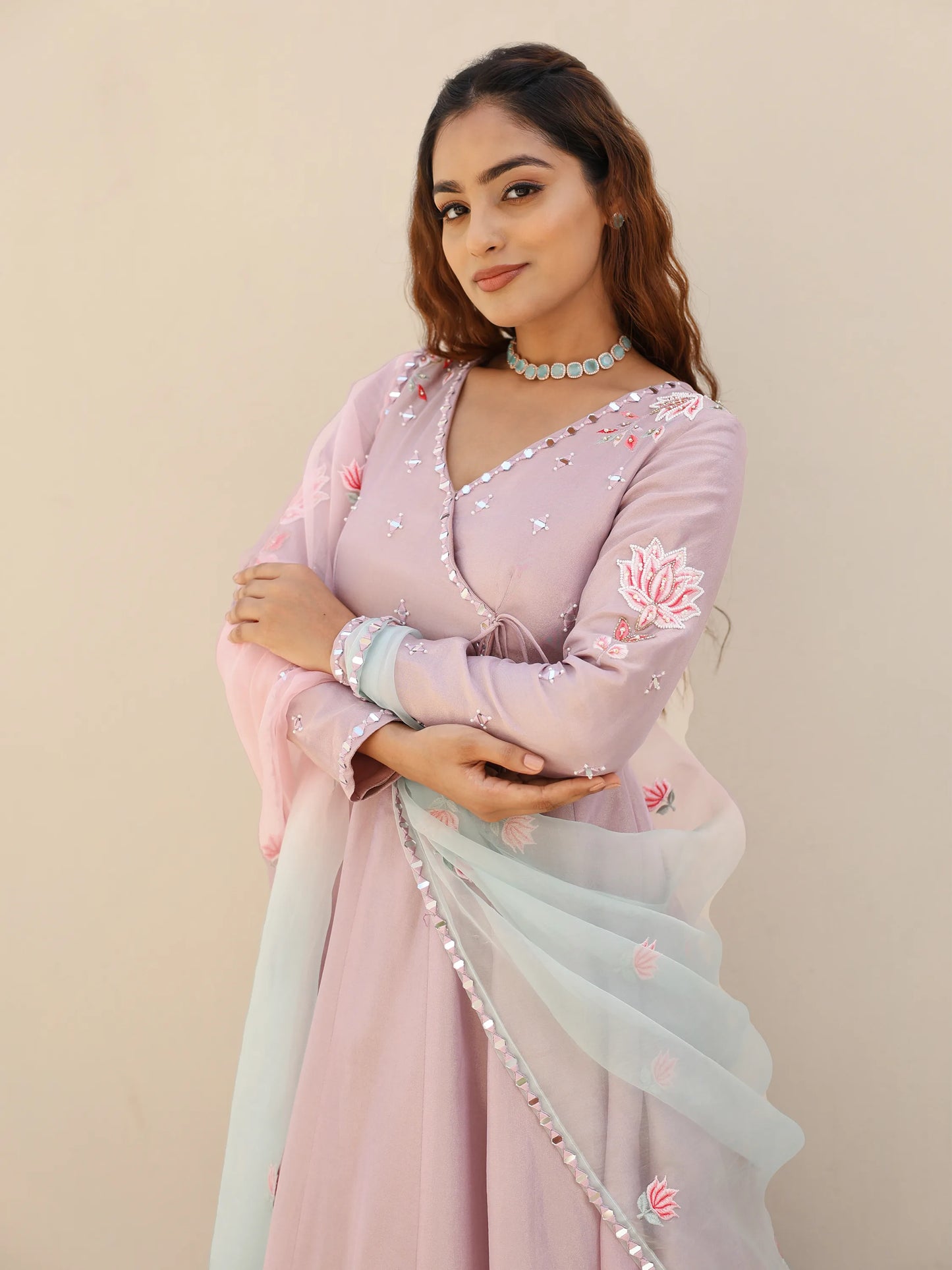 Woman in a pink traditional Anarkali adorned with lotus motifs and mirror work.