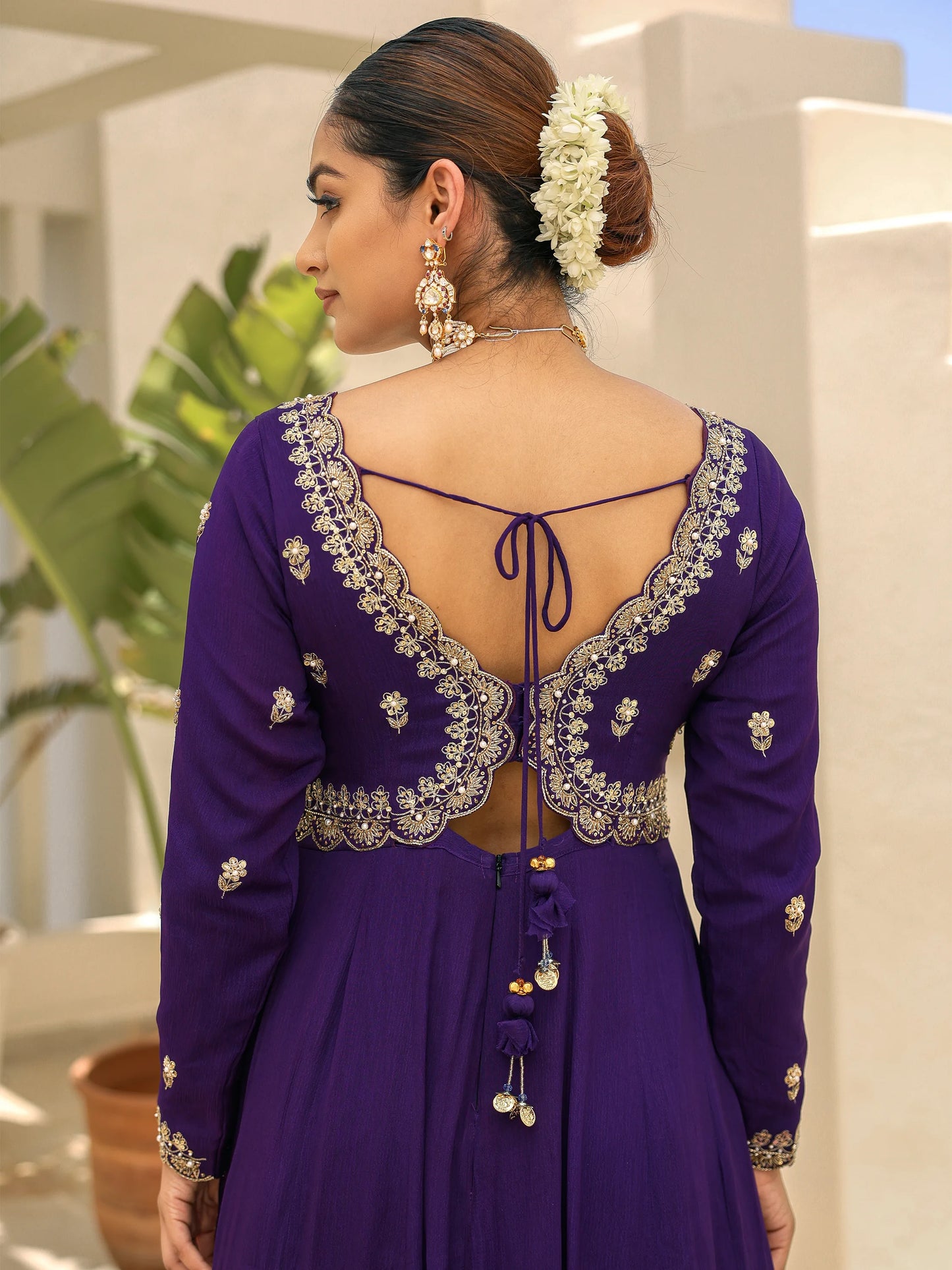 Back view of a woman wearing a purple anarkali with hand embroidery on the blouse.