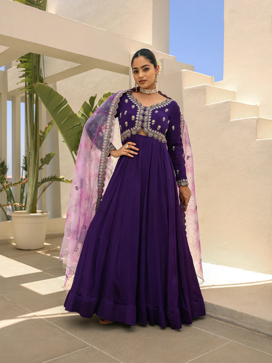 Woman in a purple anarkali with a lavender dupatta standing in a modern setting.