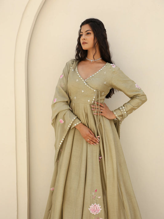 Woman wearing a sage green anarkali with floral motifs and mirror work.