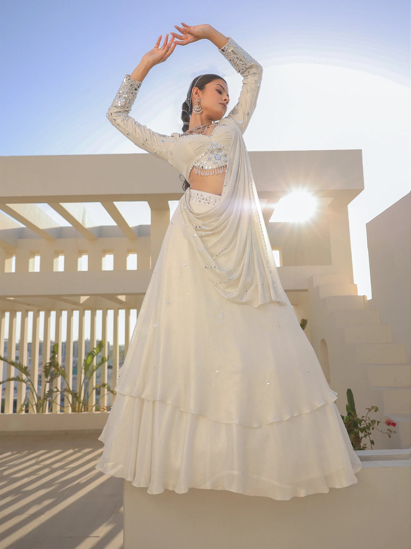 A woman in a white traditional saree outfit on a rooftop with a clear sky